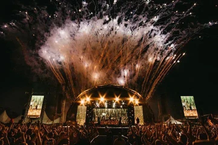 Fireworks over a crowded concert stage at night