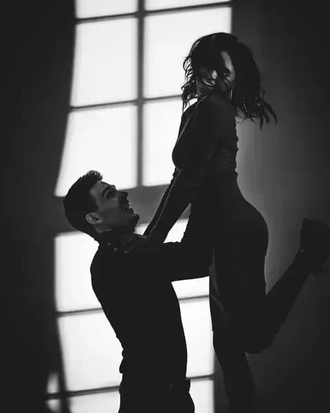 A couple dancing in silhouette against a bright window