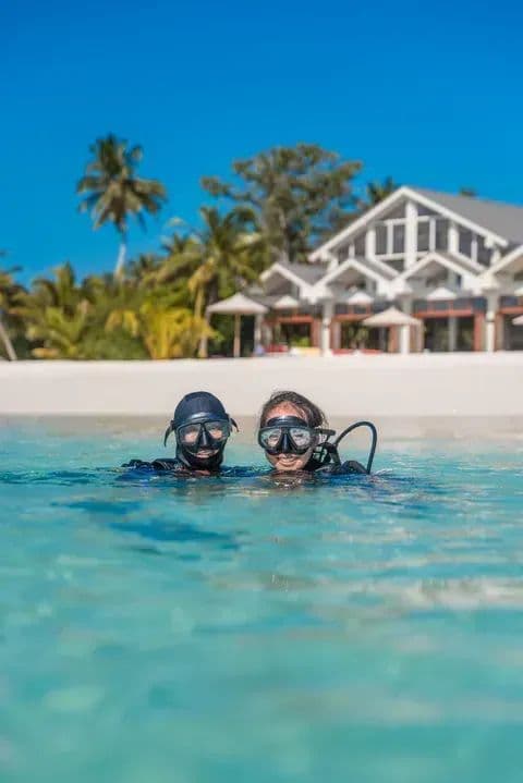 Two scuba divers surfacing in clear blue water